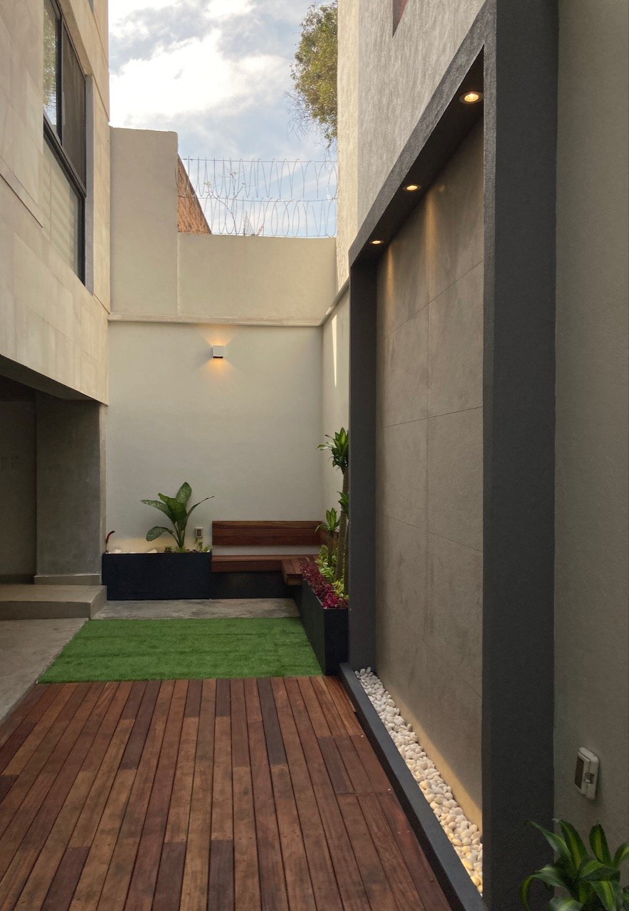 Patio interior con deck de madera, banca y jardineras